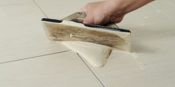 hand-man-holding-rubber-float-filling-joints-with-grout_191163-2011