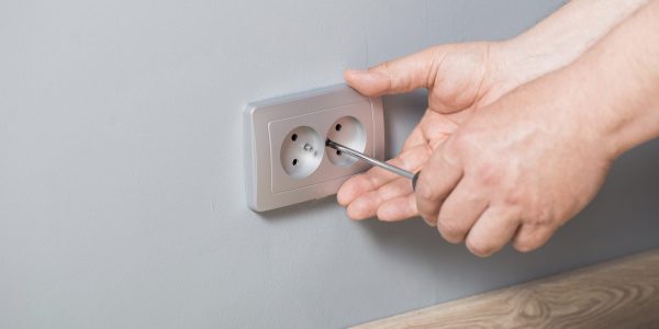 man-installs-electrical-outlet-gray-wall