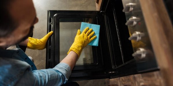top-view-selective-focus-male-hands-that-cleaning-oven-while-wiping-surface-with-cleaning-cloth-holding-lid_259150-24583