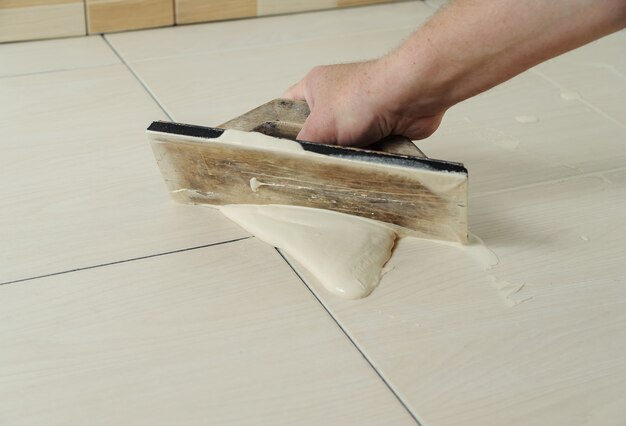 hand-man-holding-rubber-float-filling-joints-with-grout_191163-2011