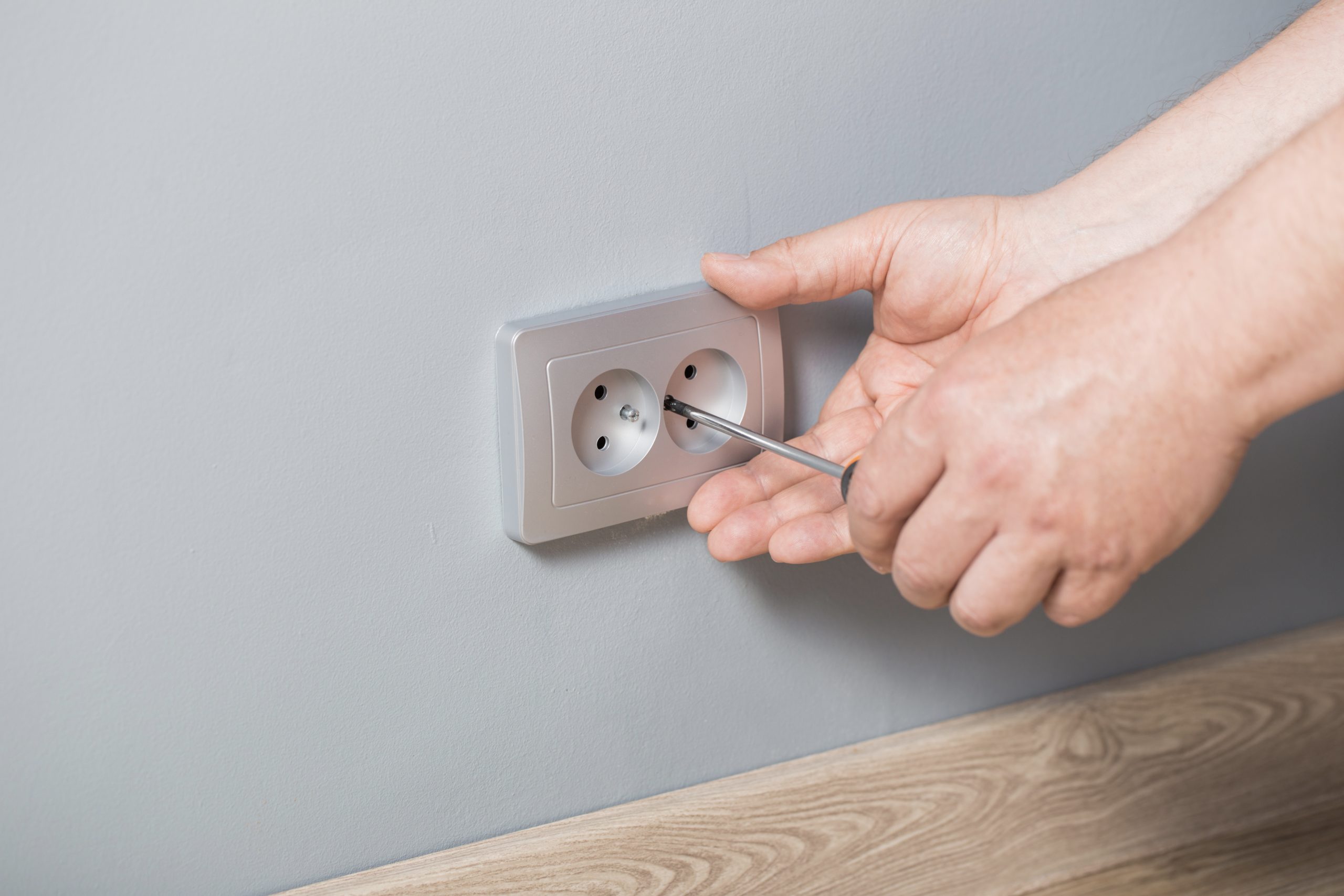 man-installs-electrical-outlet-gray-wall