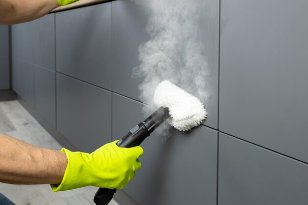 mans-hand-protective-glove-cleans-kitchen-facade-with-steam_182033-212