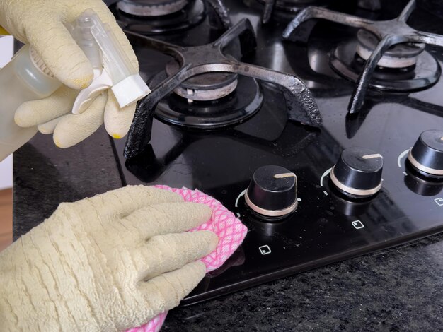 person-cleaning-modern-black-gas-stove-with-pink-cloth-spray-cleaner-eliminate-fat_597321-1121