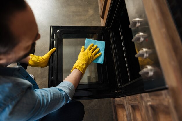 top-view-selective-focus-male-hands-that-cleaning-oven-while-wiping-surface-with-cleaning-cloth-holding-lid_259150-24583